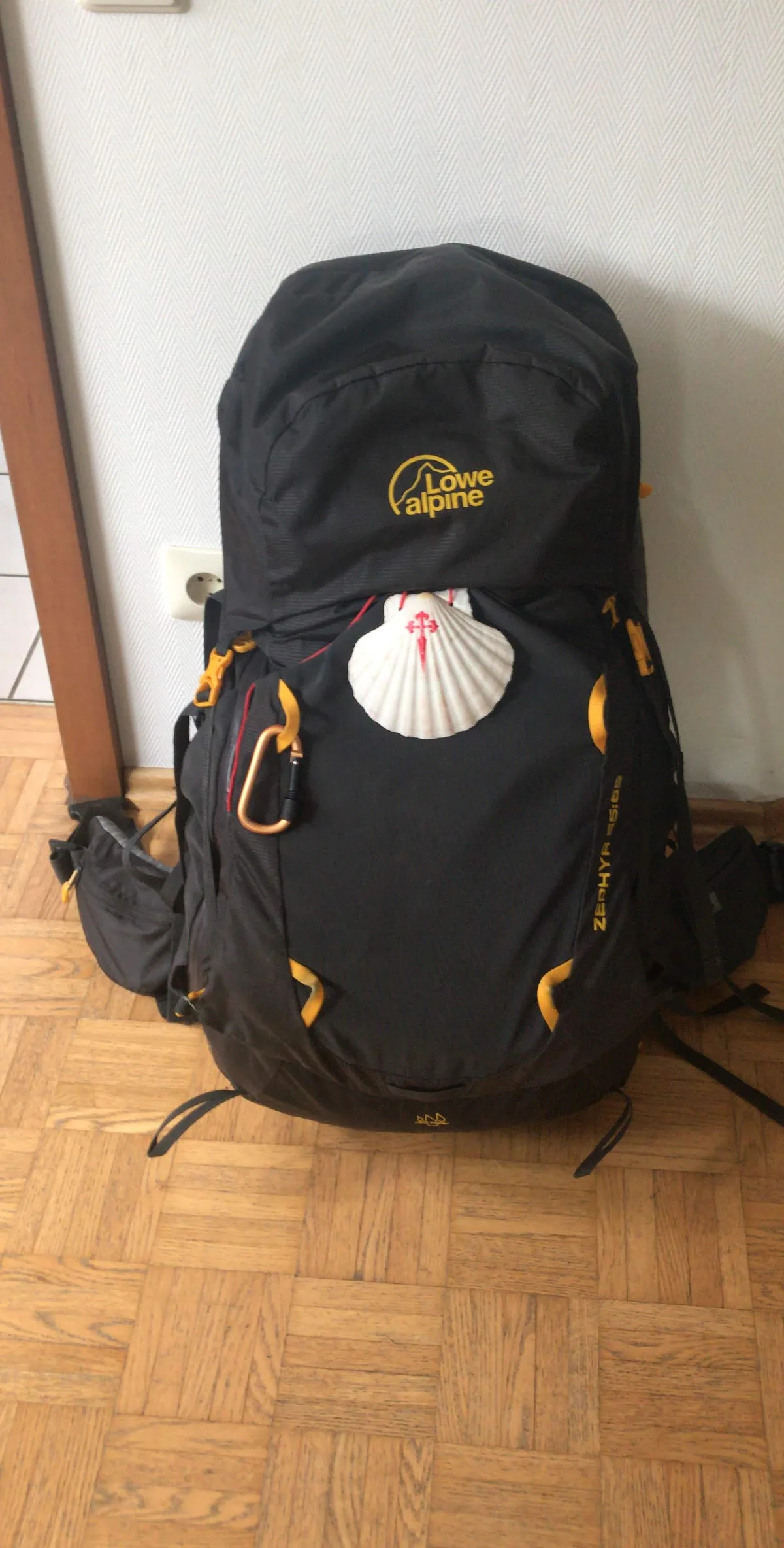 Ein gepackter Rucksack mit Pilgermuschel steht im Flur.