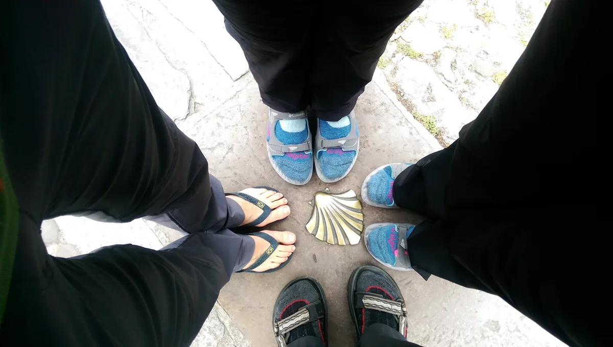 Pilgerschuhe bilden einen Kreis um eine Muschel im Boden.