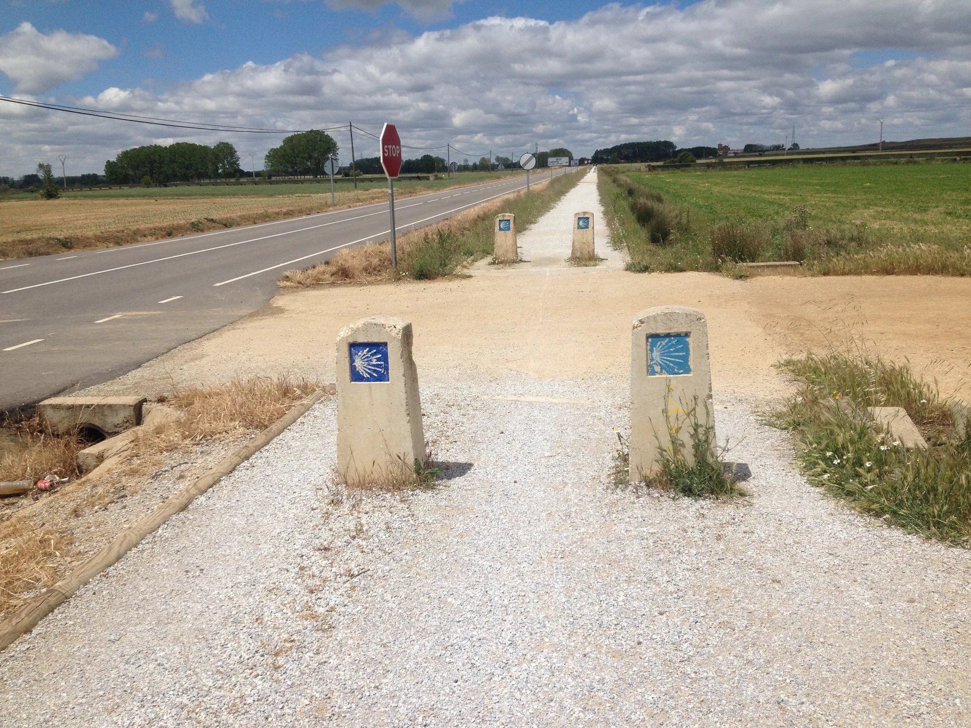 Ein weiter Pilgerweg zwischen Feldern in der Meseta.